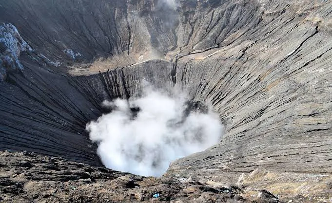 Asap belerang putih tebal mengepul dari kawah Gunung Bromo yang aktif, menunjukkan kekuatan alam.