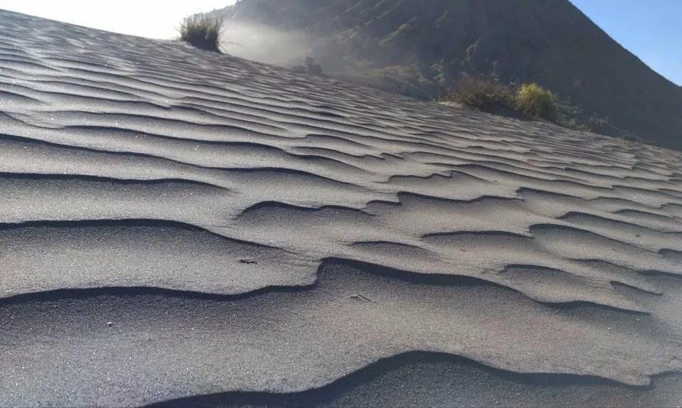 Butiran pasir halus di pasir berbisik Bromo yang ditiup angin, menunjukkan fenomena suara bisikan.