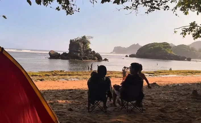 Tenda camping berdiri di pinggir Pantai Kondang Merak saat senja